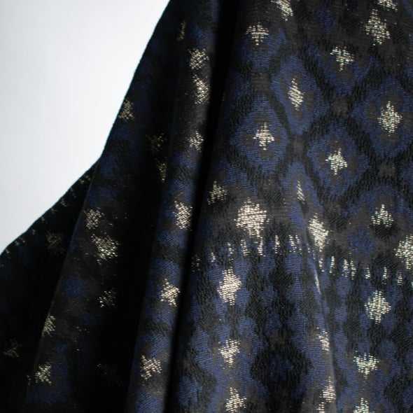 The golden metallic threads of this Italian jacquard create a diamond pattern, bordered in a black diamond shape that is just stunning.  A soft textured hand and medium weight make it perfect for a stylish jacket! Photo of fabric drape.