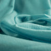 Merino Wool Jersey knit in a gorgeous blue turquoise, it makes a perfect layering piece.  This fabric has a soft hand and is light and flowy, perfect for a top or cardigan.  A generous width at 60 inches and a mechanical stretch.  Close up image.